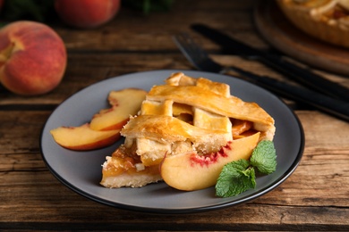 Photo of Piece of delicious fresh peach pie served on wooden table, closeup
