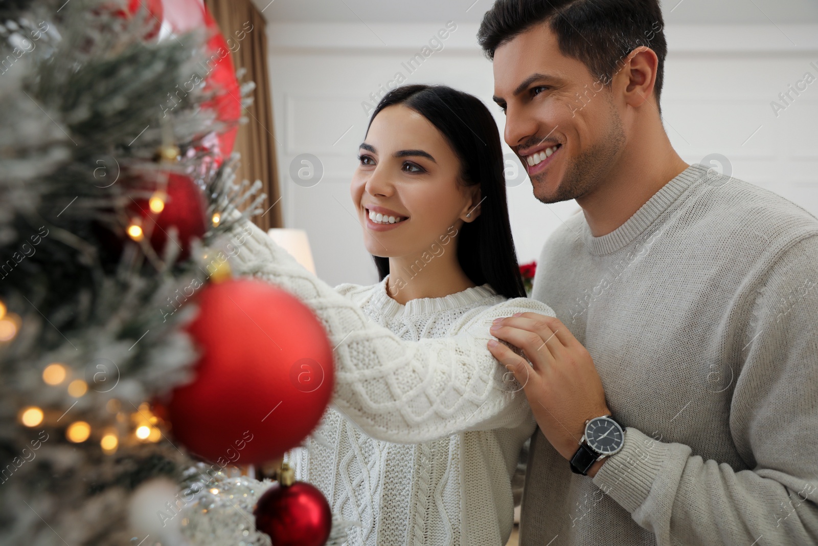 Photo of Happy couple decorating Christmas tree at home