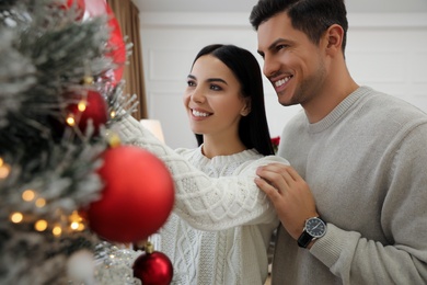 Photo of Happy couple decorating Christmas tree at home