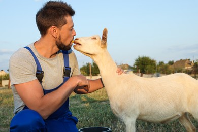 Photo of Man feeding goat at farm. Animal husbandry