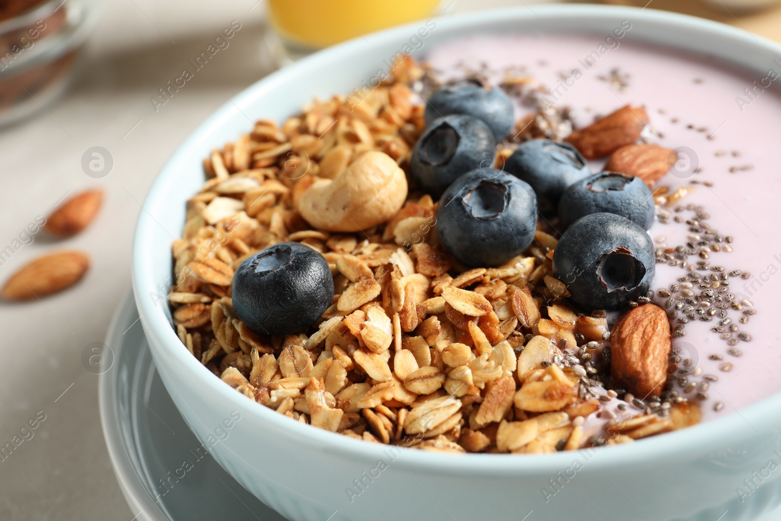 Photo of Bowl of tasty oatmeal with blueberries and yogurt on table, closeup