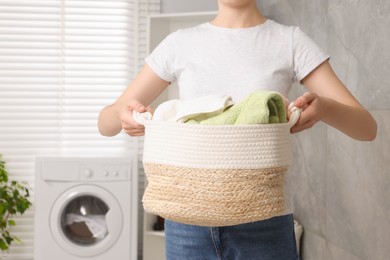 Woman with basket full of laundry in bathroom, closeup