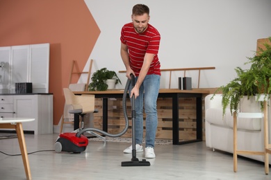 Young man using vacuum cleaner at home