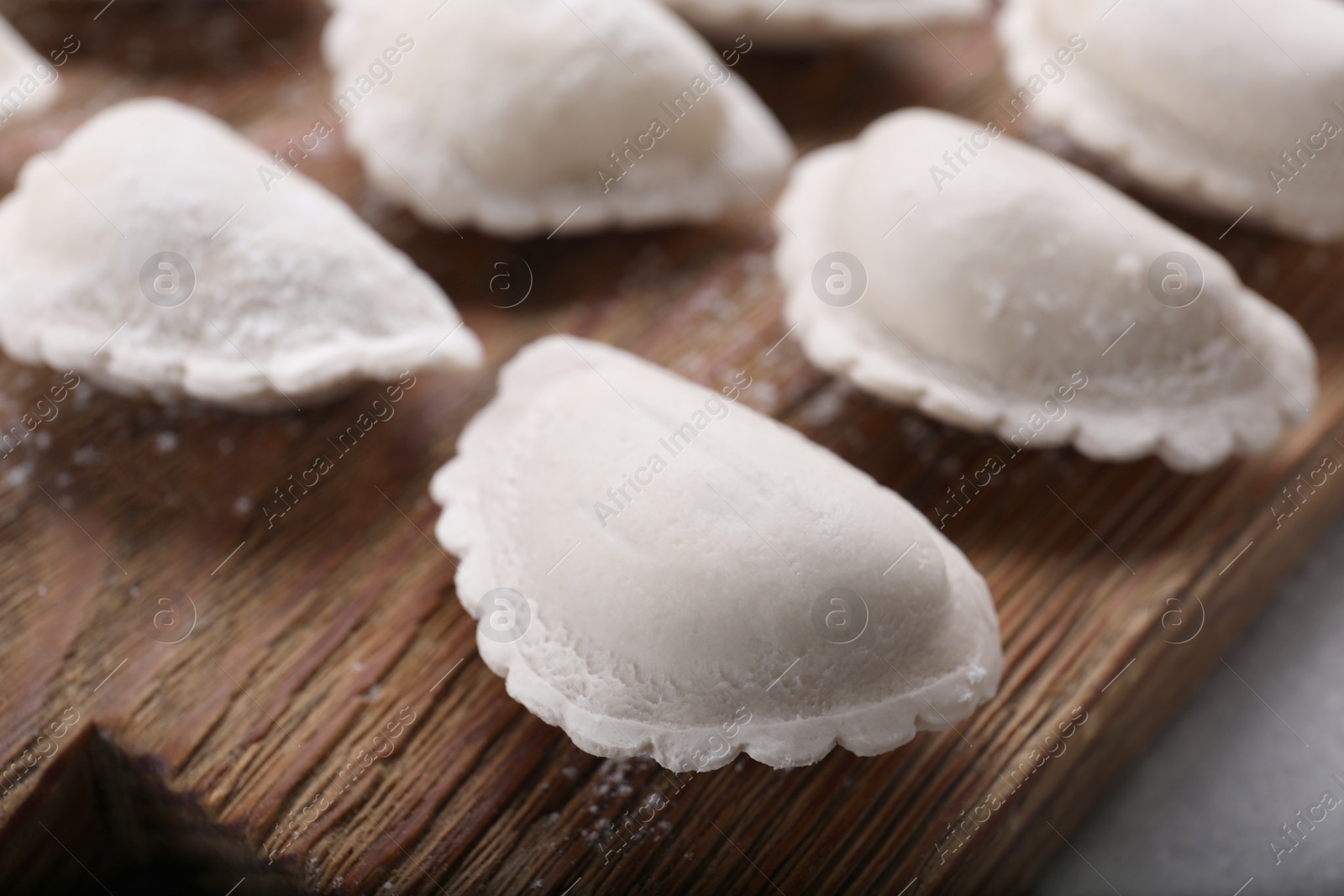 Photo of Raw dumplings (varenyky) on grey table, closeup