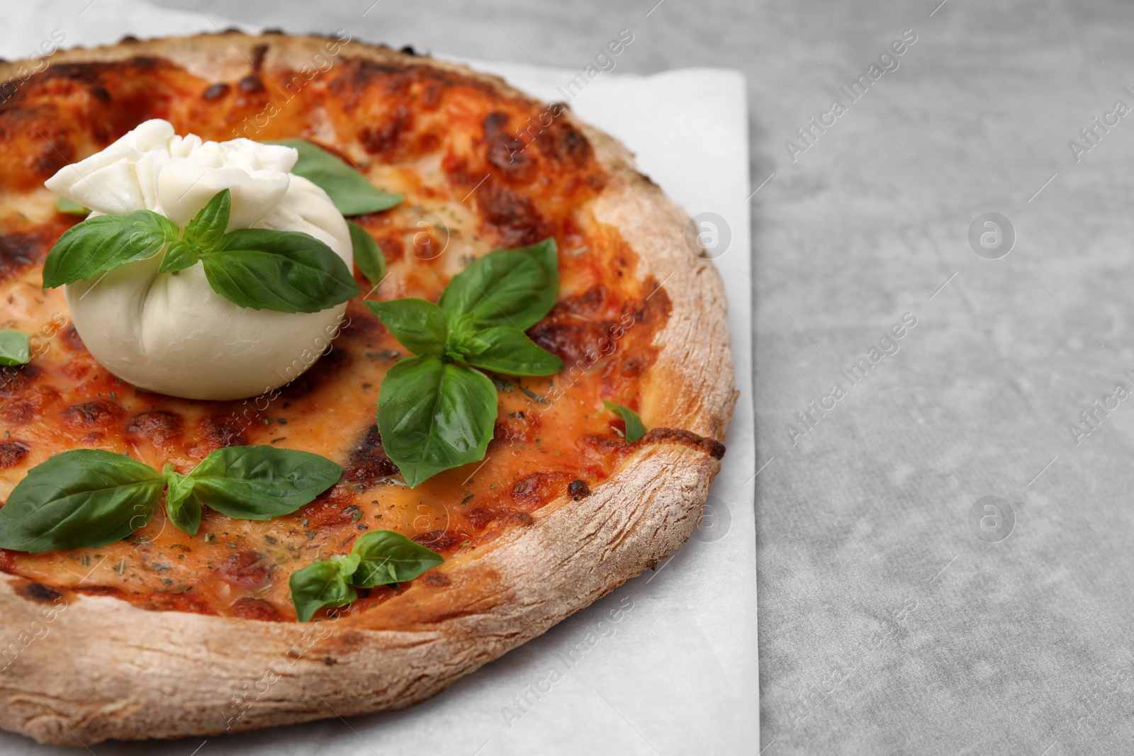 Photo of Delicious pizza with burrata cheese and basil on gray table, closeup. Space for text