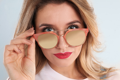 Photo of Young woman wearing stylish sunglasses on light grey background