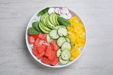 Delicious poke bowl with salmon and vegetables on wooden table, top view