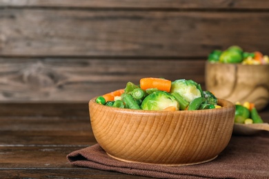 Bowl with different frozen vegetables on wooden table