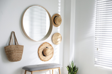 Stylish round mirror hanging on white wall in room