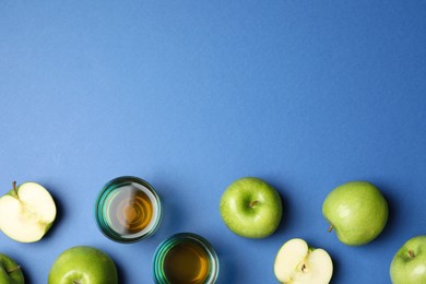 Photo of Ripe apples and juice on blue background, flat lay. Space for text