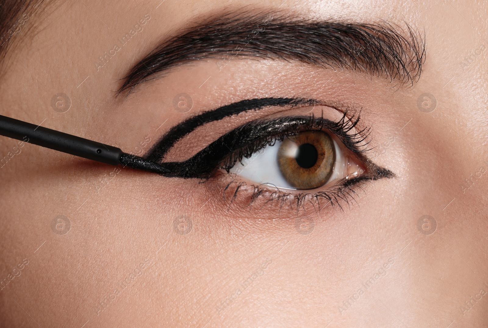 Photo of Beautiful woman applying black eyeliner, closeup view