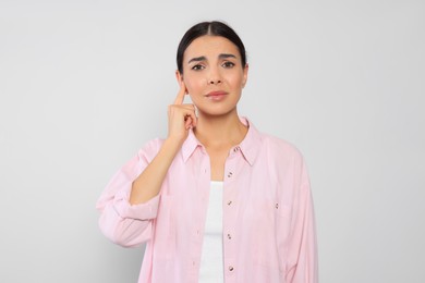 Photo of Young woman suffering from ear pain on light grey background
