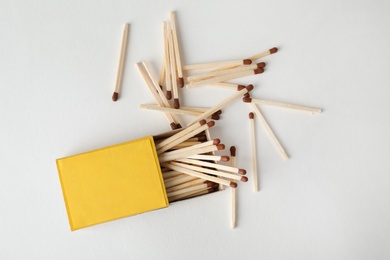 Photo of Cardboard box and matches on light background, top view. Space for design