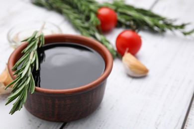 Organic balsamic vinegar and cooking ingredients on white wooden table, closeup