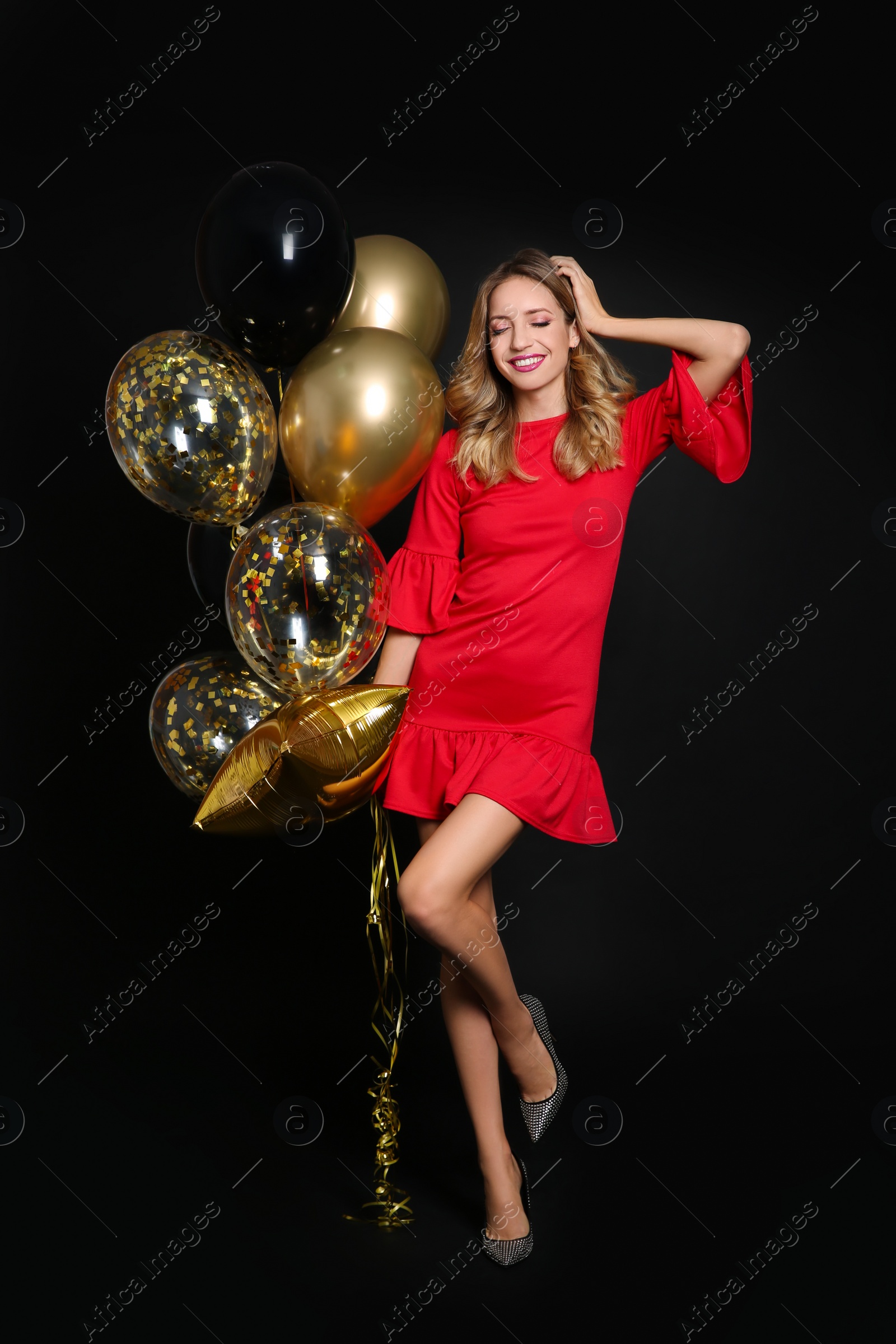 Photo of Happy woman with air balloons on black background. Christmas party