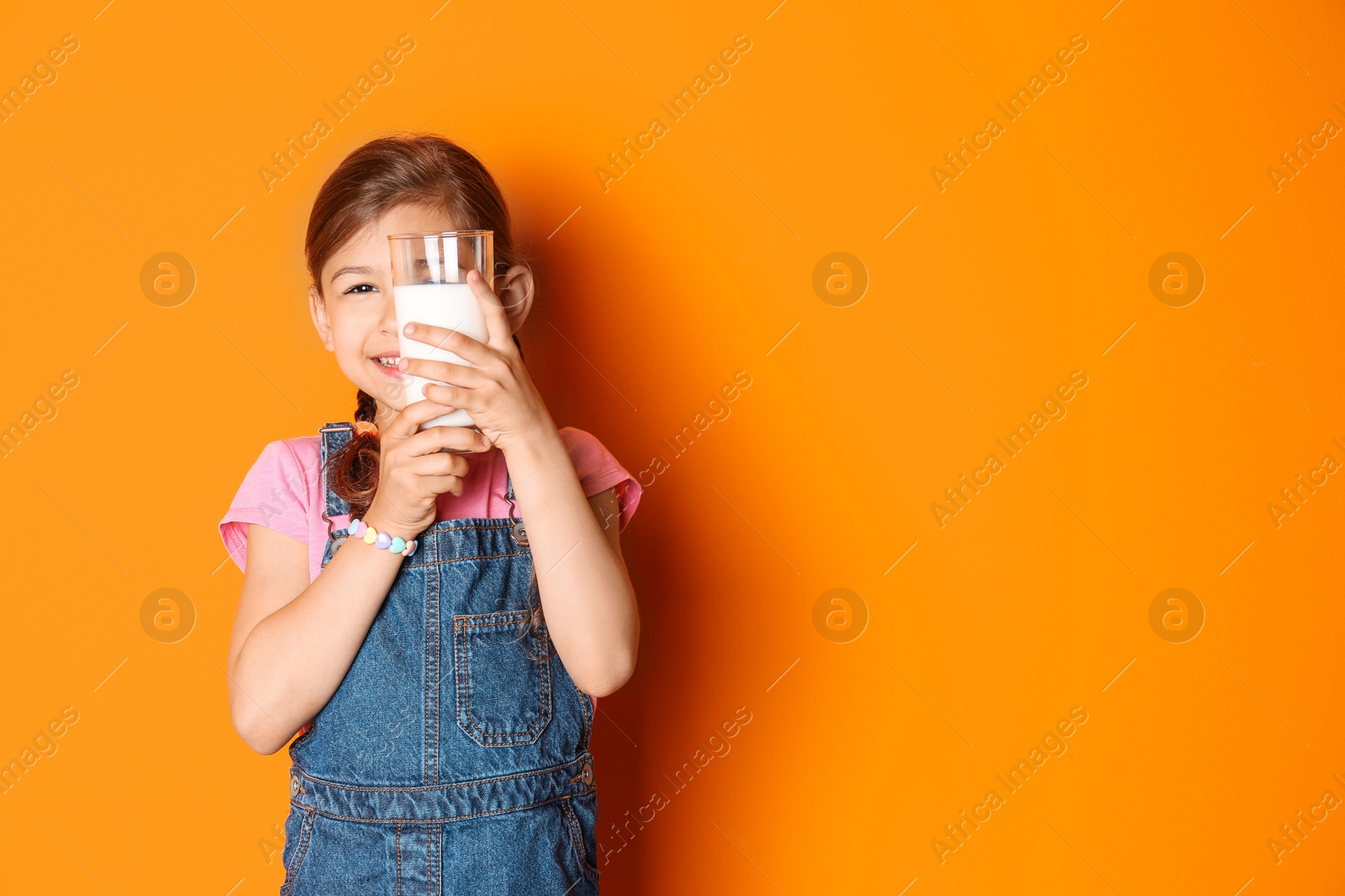 Photo of Cute little girl with glass of milk on color background