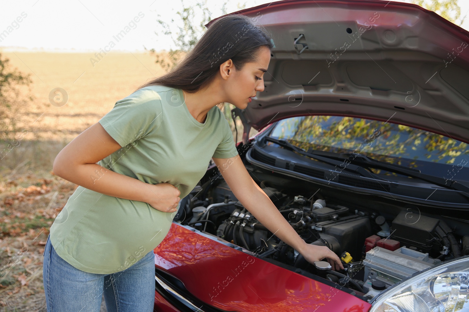 Photo of Stressed pregnant woman near broken car outdoors