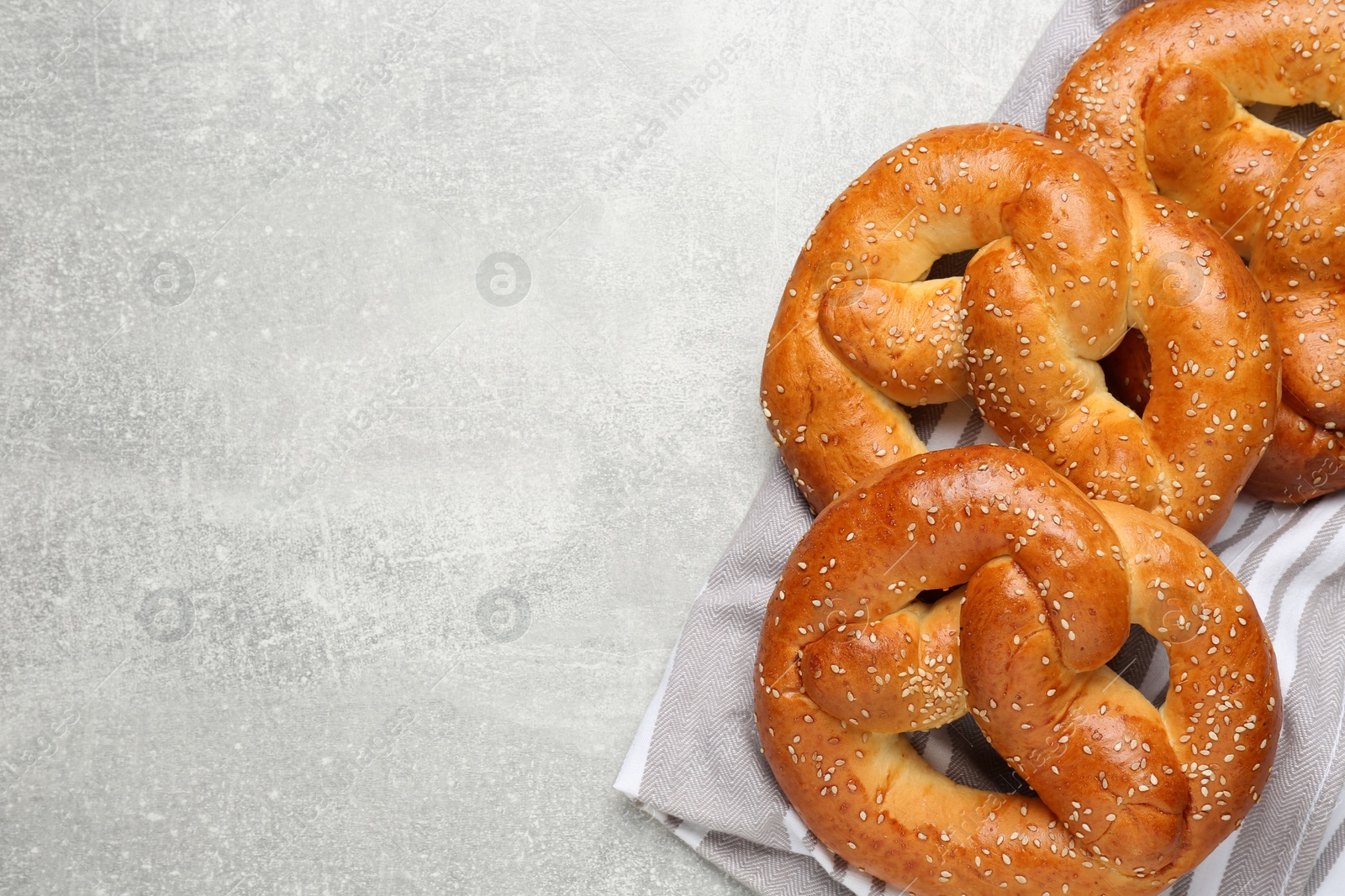 Photo of Tasty freshly baked pretzels on light grey table, flat lay. Space for text