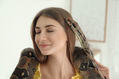 Photo of Young woman with boa constrictor at home. Exotic pet