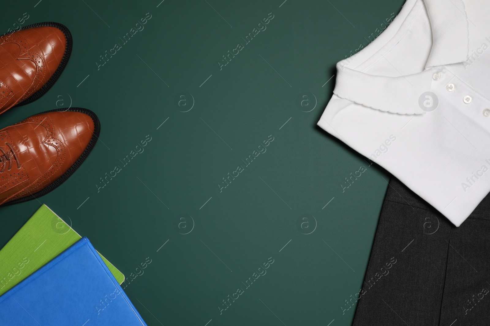 Photo of New stylish school uniform and notebooks on green background, flat lay. Space for text