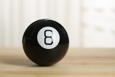 Photo of Magic eight ball with on wooden table, closeup. Space for text
