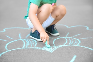 Photo of Little child drawing with chalk on asphalt
