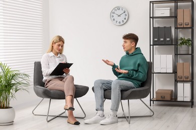 Psychologist working with teenage boy in office