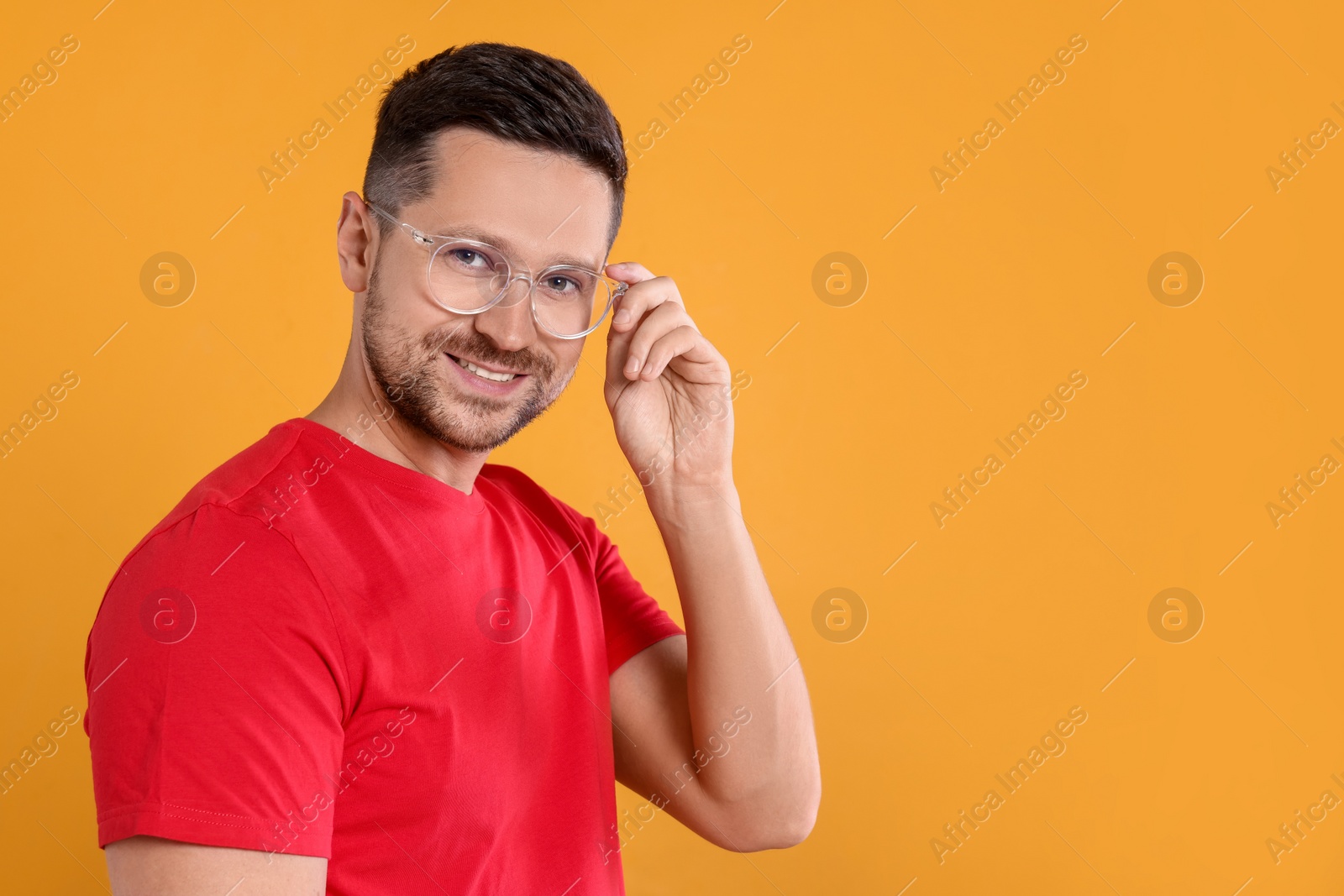 Photo of Portrait of happy man in stylish glasses on yellow background. Space for text