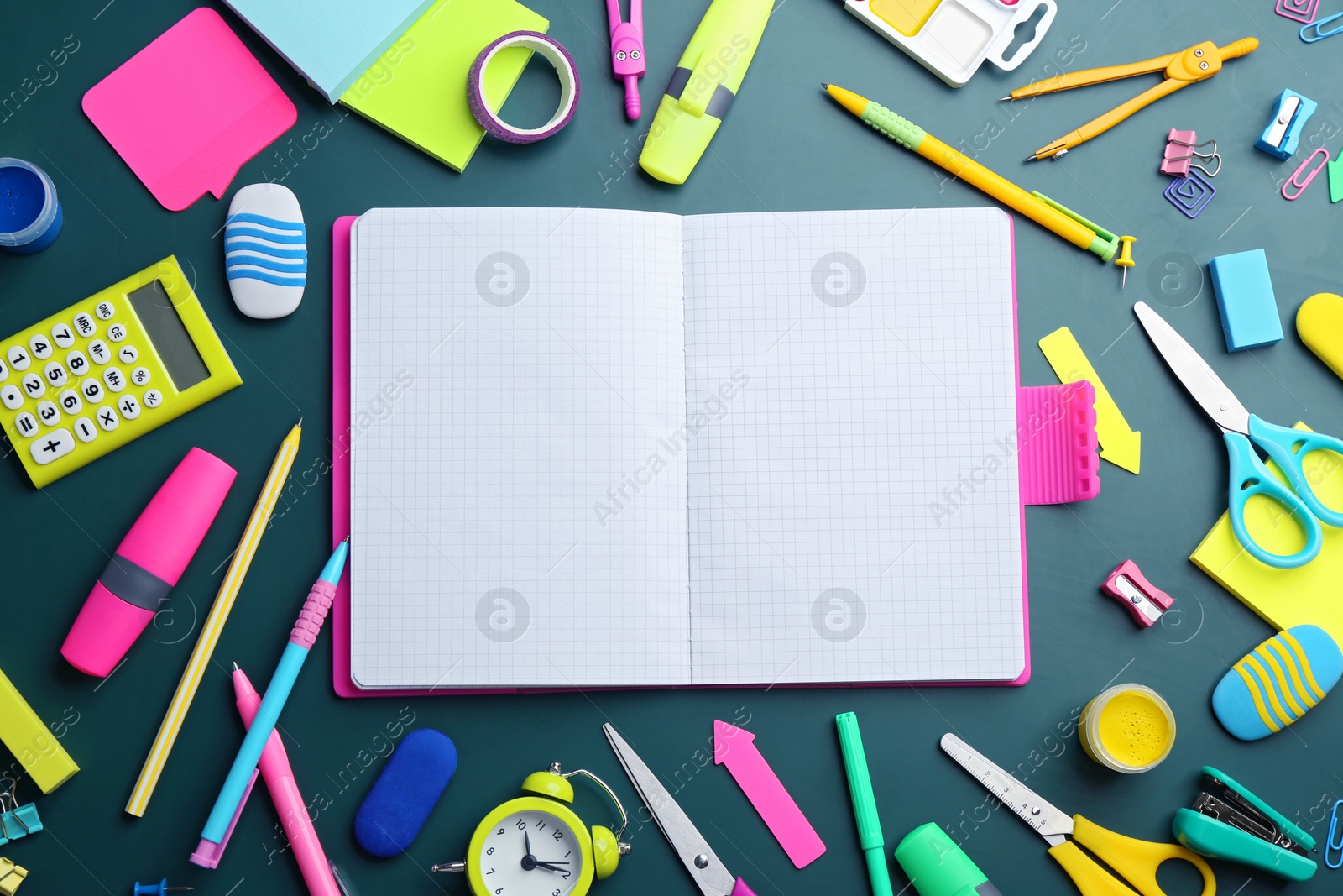 Photo of Different bright school stationery and blank notebook on green background, flat lay. Space for text