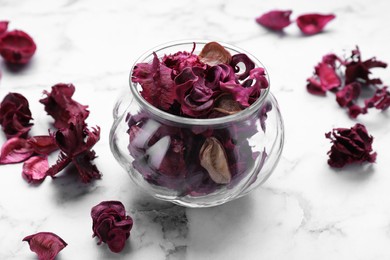 Aromatic potpourri of dried flowers in glass jar on white marble table