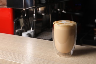 Photo of Glass cup of fresh aromatic coffee on wooden counter in cafe, space for text