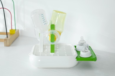 Dryer with baby bottles and nipples after sterilization on white table