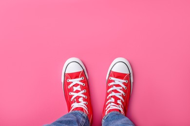 Photo of Woman in stylish gumshoes on pink background, top view. Space for text