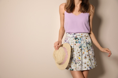 Photo of Young woman wearing floral print skirt with straw hat on beige background, closeup. Space for text