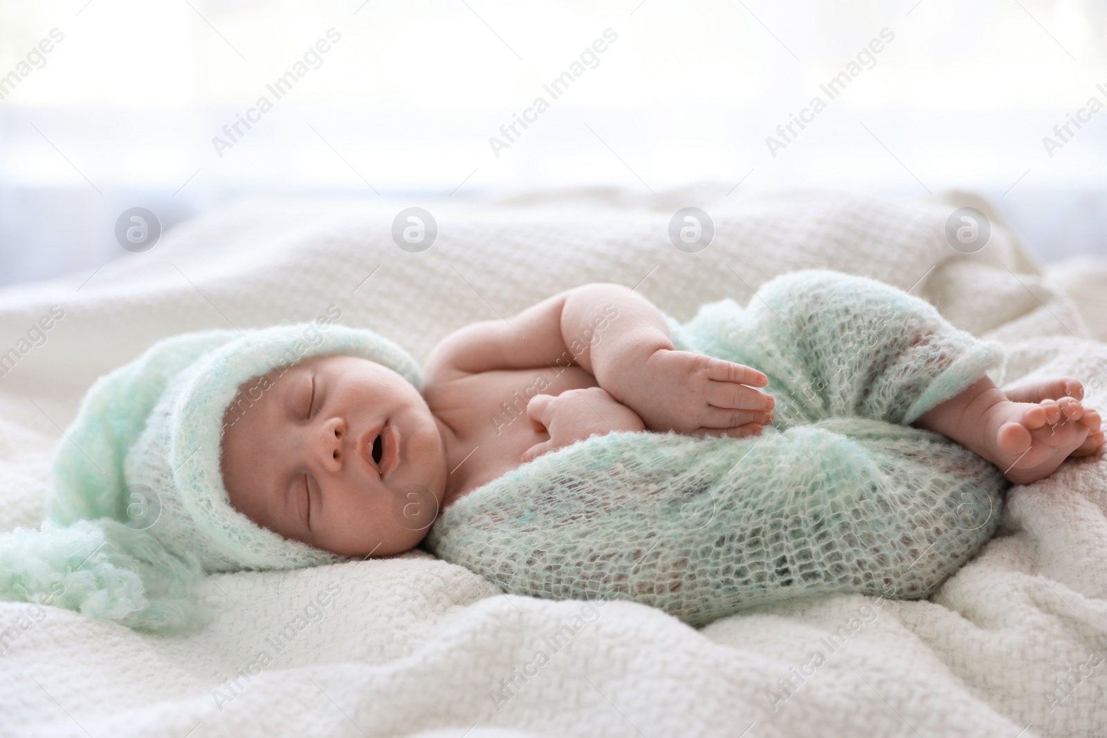 Photo of Cute newborn baby in warm hat sleeping on white plaid