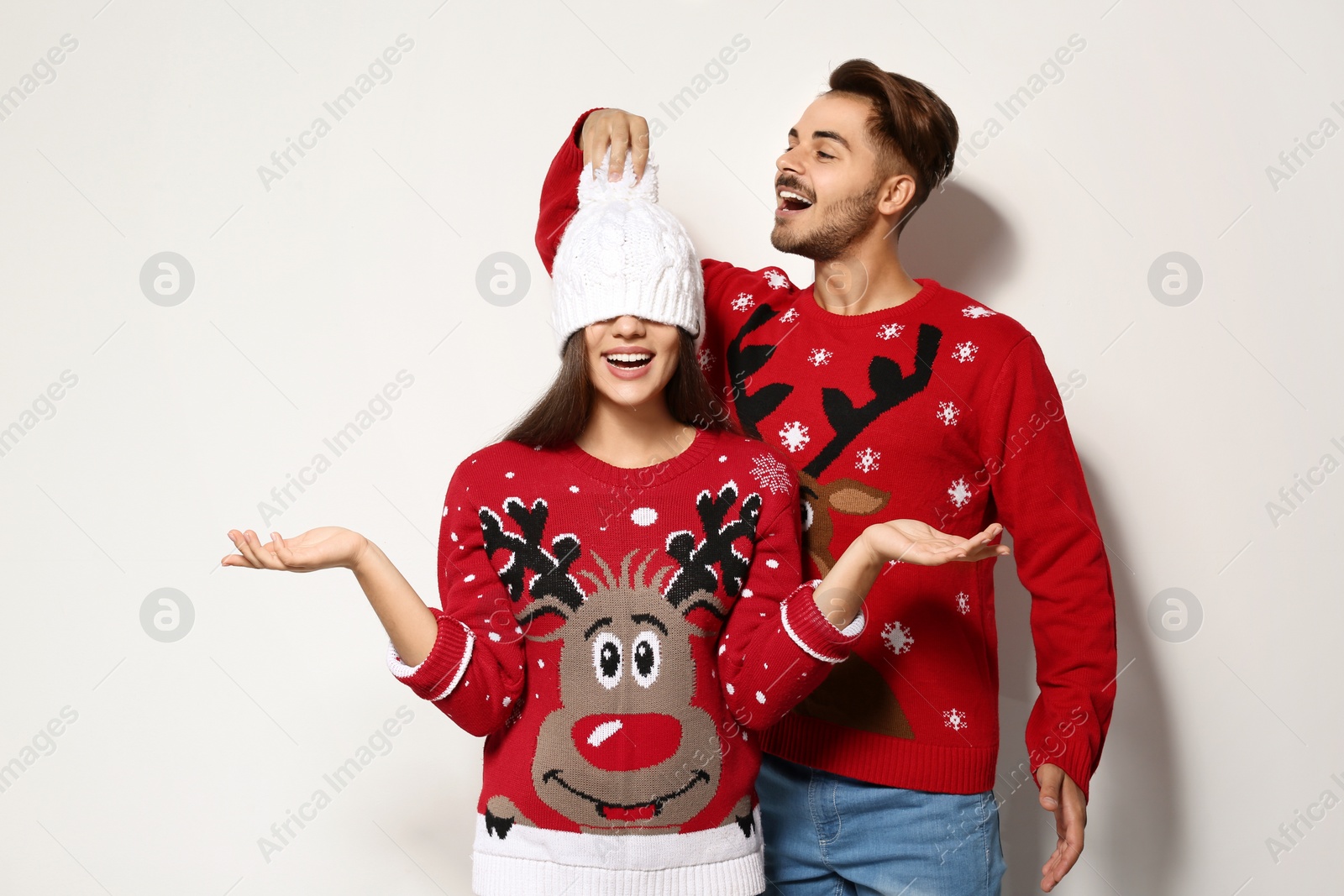 Photo of Young couple in Christmas sweaters on white background