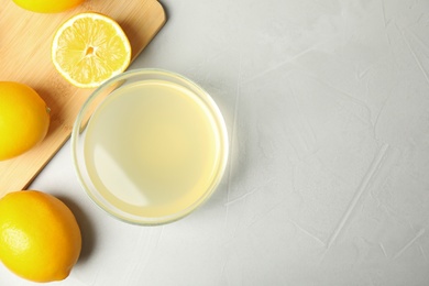 Freshly squeezed juice and lemons on light table, flat lay. Space for text