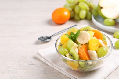 Photo of Delicious fresh fruit salad in bowl on table, space for text