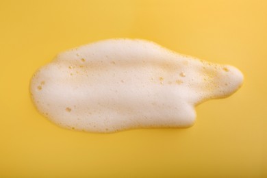 Photo of Sample of fluffy foam on yellow background, top view