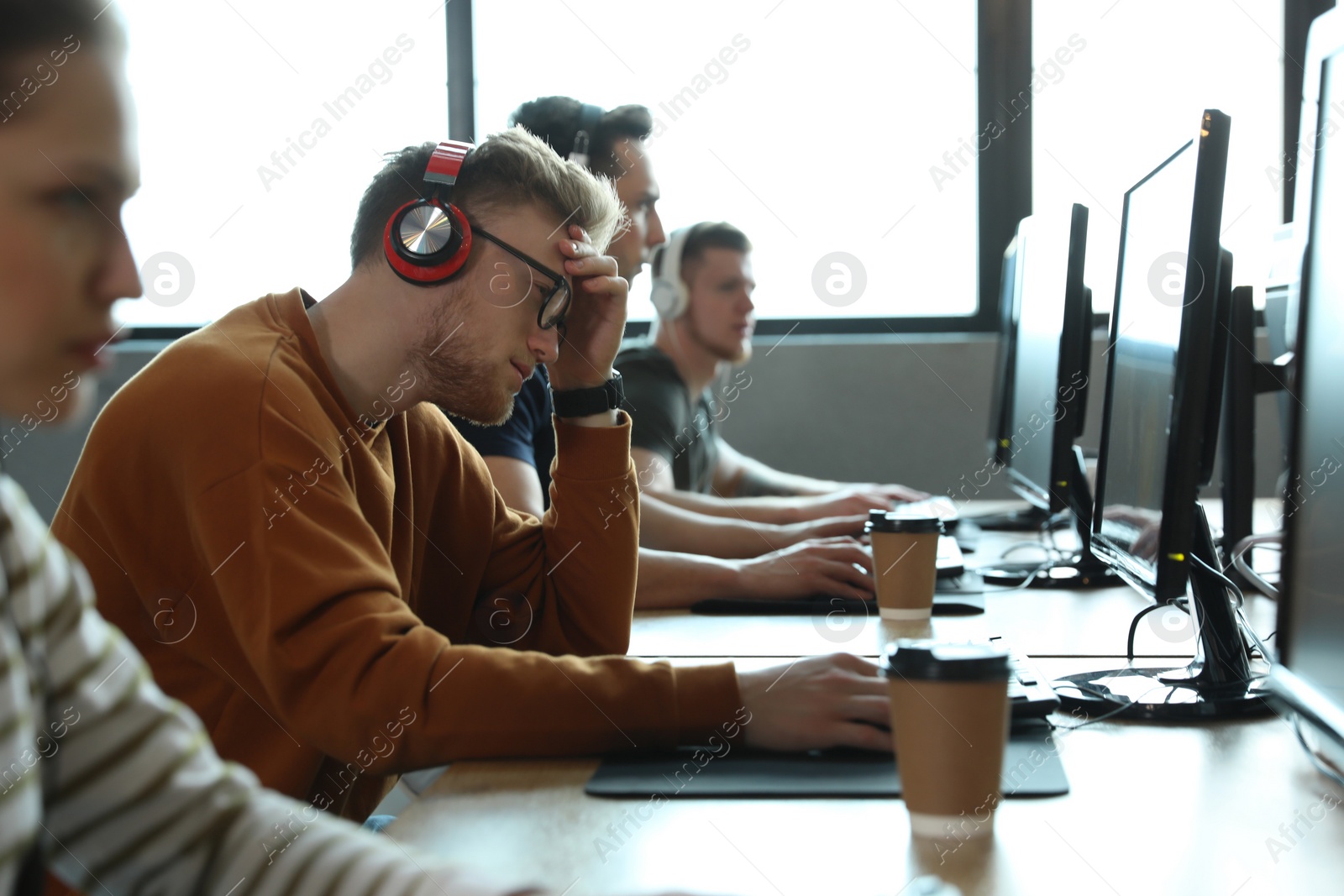 Photo of Group of people playing video games in internet cafe