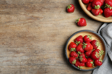 Delicious ripe strawberries on wooden table, flat lay. Space for text