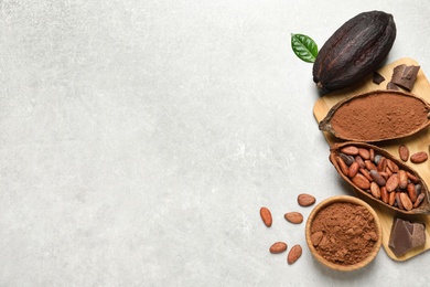 Flat lay composition with cocoa pods, powder and beans on light table. Space for text