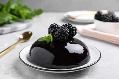 Photo of Delicious jelly with blackberries and mint on grey table