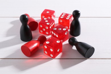 Red game dices and color pieces on white wooden table