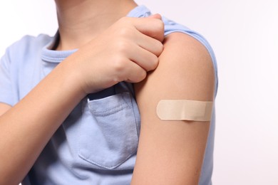 Photo of Boy with sticking plaster on arm after vaccination against white background, closeup