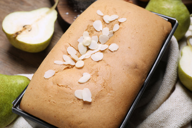 Photo of Tasty bread with almond flakes and pears on table, closeup. Homemade cake