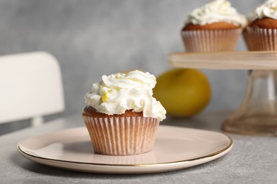 Photo of Delicious cupcake with cream and lemon zest on gray table, closeup