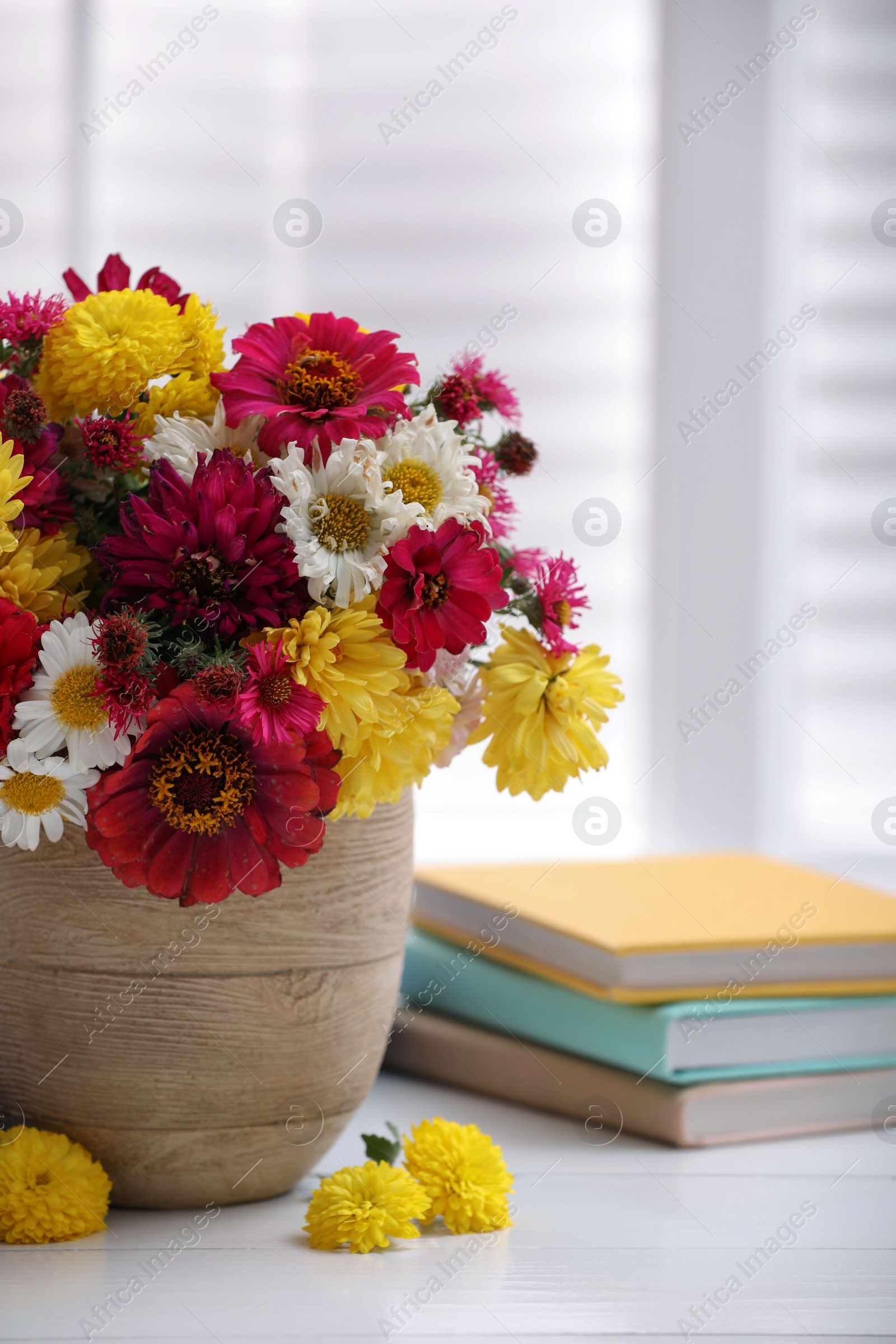 Photo of Beautiful bouquet and books on white wooden table near window