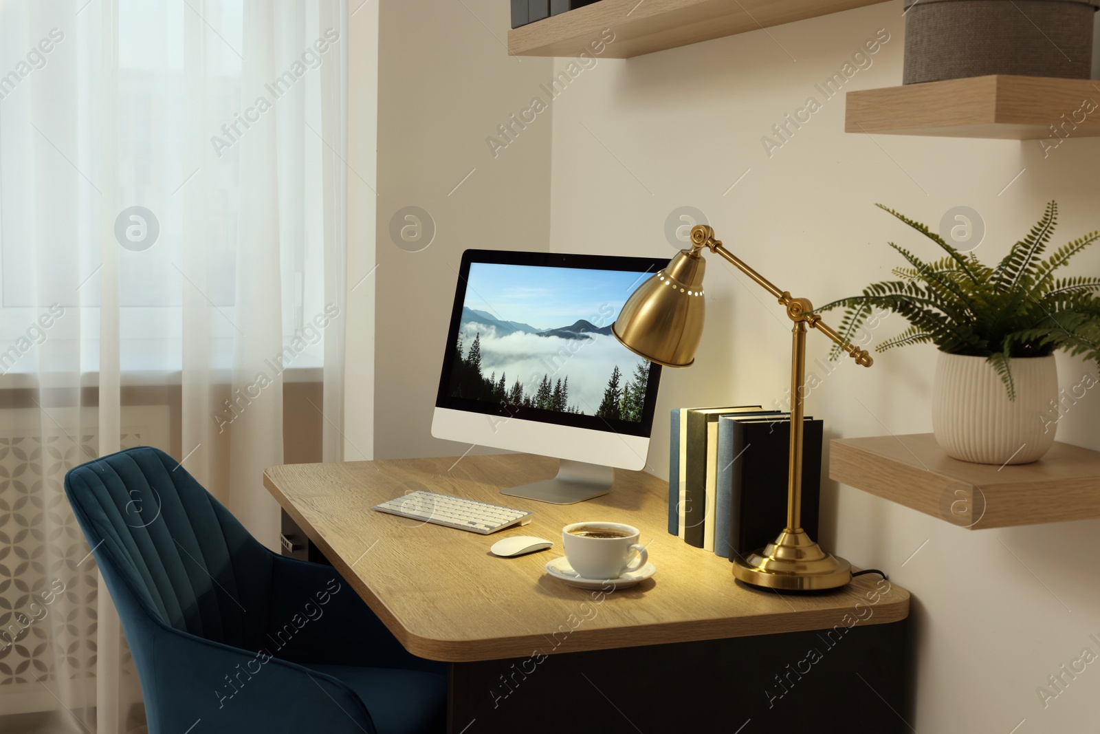 Photo of Cozy workspace with computer on wooden desk and comfortable chair at home