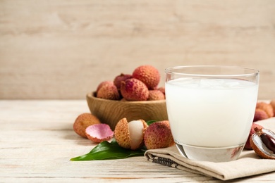 Photo of Fresh lychee juice and fruits on white wooden table. Space for text